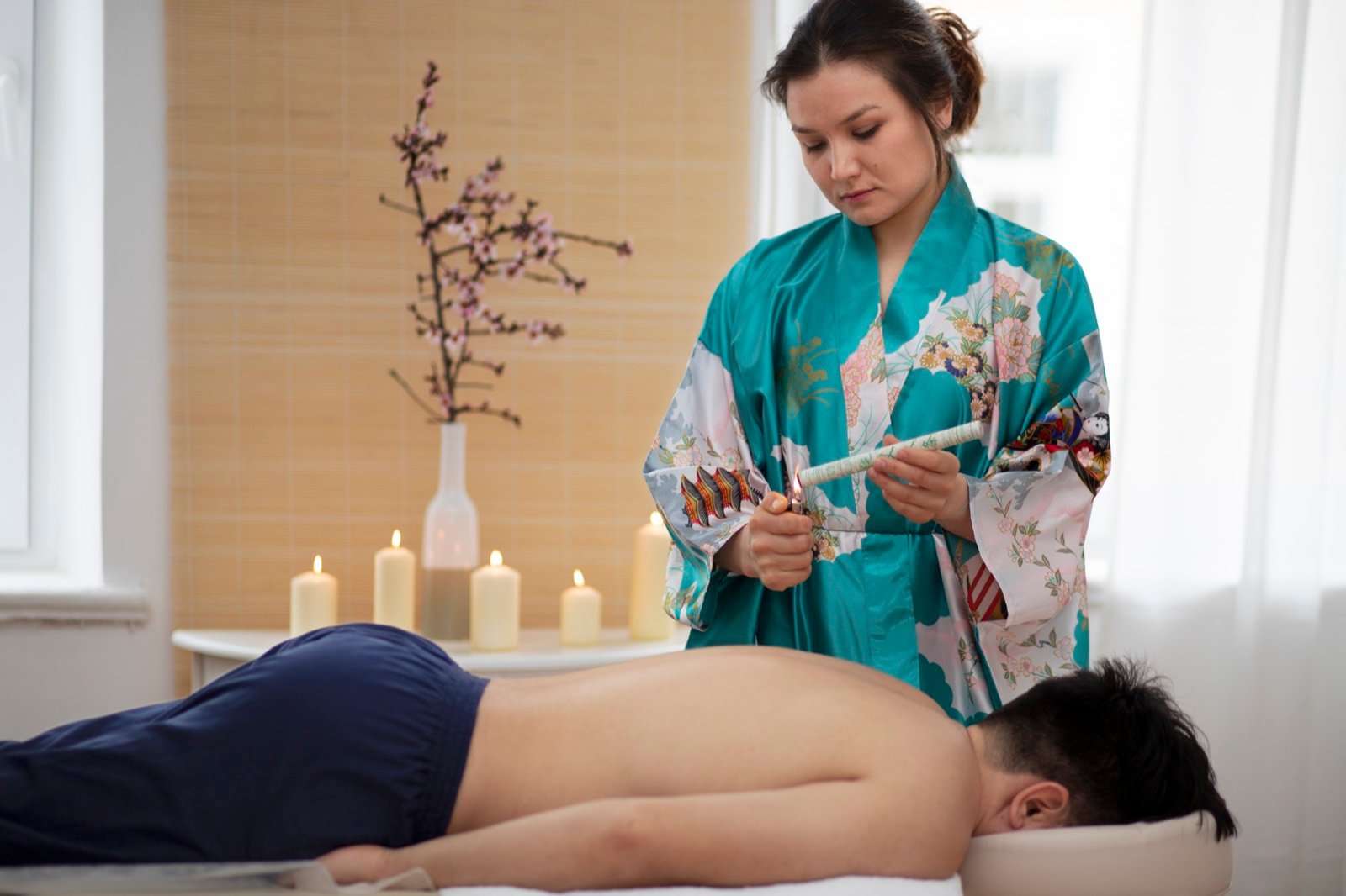 A practitioner lighting a moxa stick before treatment